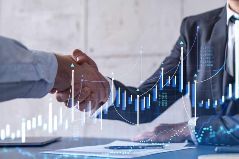 Handshake symbolizing a scalable business model with financial growth diagram over a document on the table for long-term business success